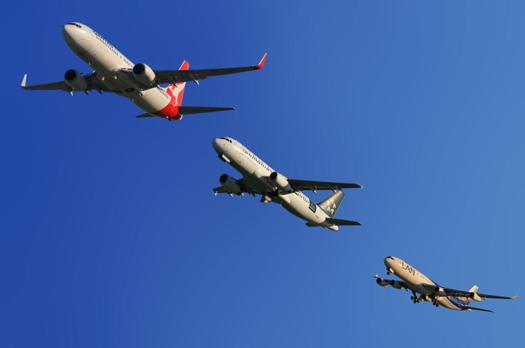 Three commercial airplanes soaring through a clear blue sky, highlighting aviation technology.