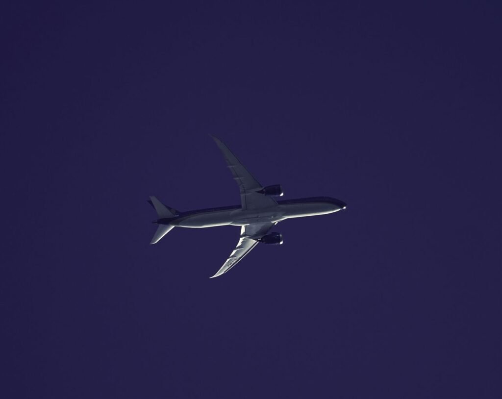A silhouette of an airplane soaring through the twilight sky, showcasing its sleek design and powerful wings.
