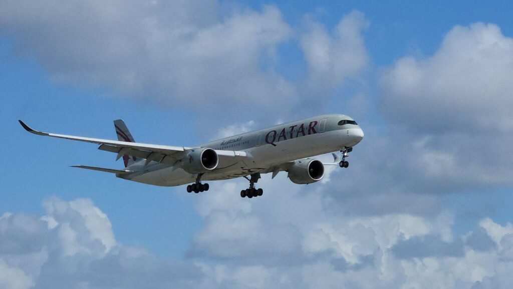 Qatar Airways Airbus A350 aircraft flying against a cloudy sky.
